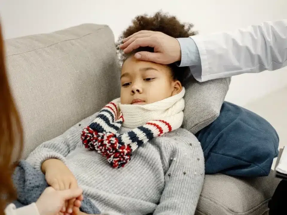 Doctor checking a sick child's temperature with a thermometer