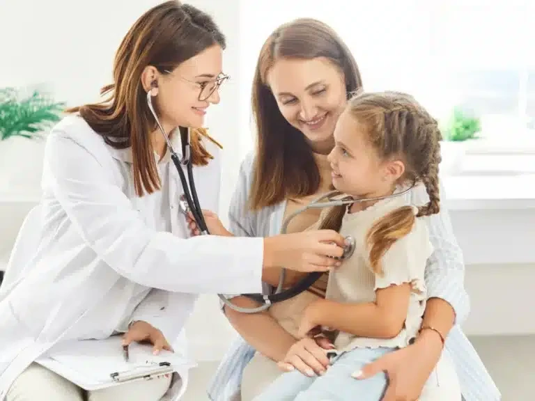 Doctor listening to a young girl's chest while her mother holds her in a clinic
