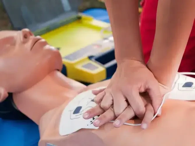 Hands giving CPR chest compressions on a mannequin during first aid training