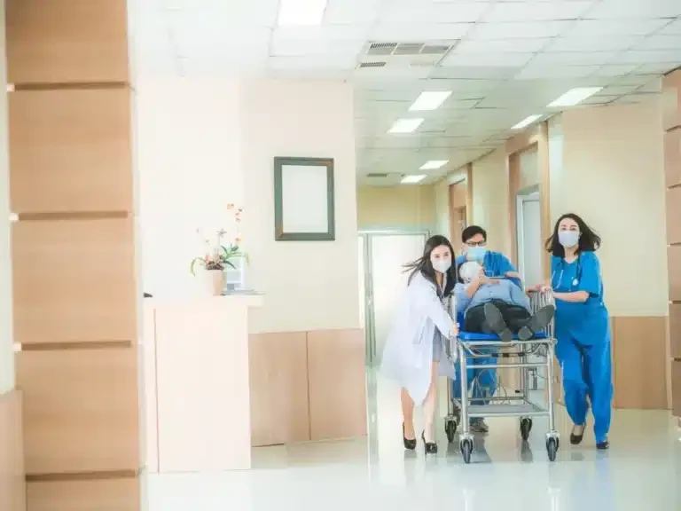 Hospital team wheeling a patient on a stretcher along a hospital corridor
