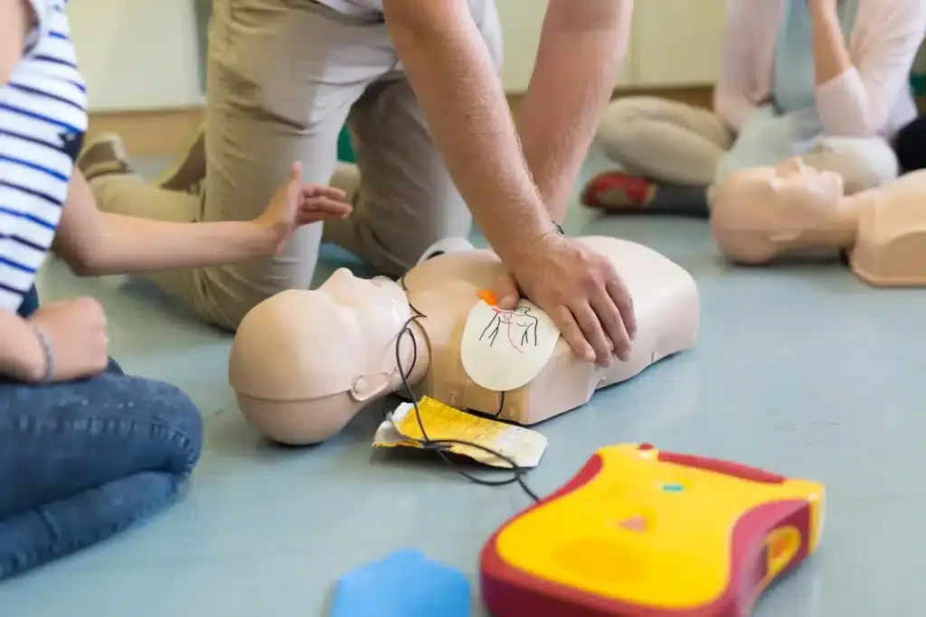 Learners practising CPR on manikins with a training defibrillator
