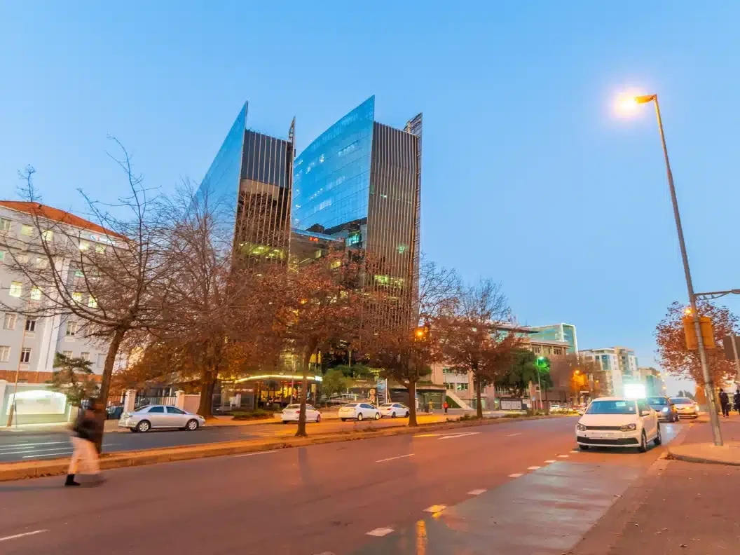 Office towers and a tree-lined street in Sandton in the evening